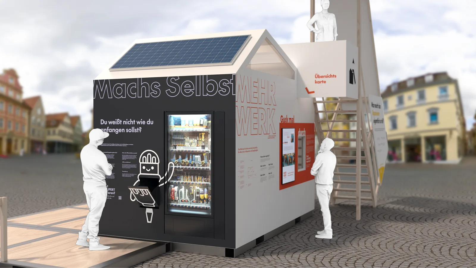 Die Automatenseite aus der Nähe: die schwarze Tafel „Machs Selbst“ mit dem gefüllten Ausleihautomaten, ein Solarpaneel auf dem Dach, zwei Menschen davor, rechts eine Treppe auf die Plattform.