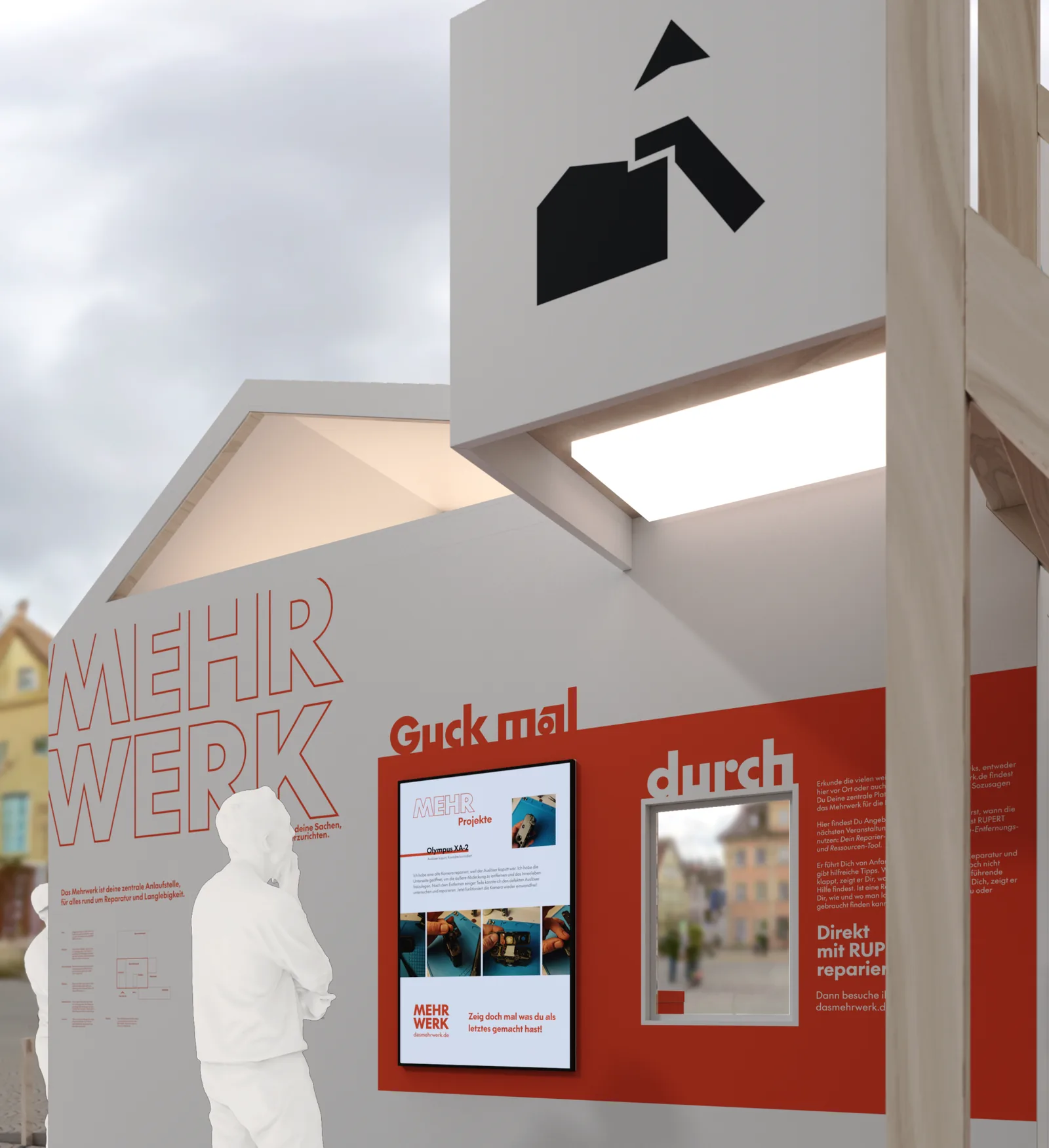 Die rote Wand „Guck mal durch“ mit Bildschirmen und dem Schriftzug MEHR WERK, davor zwei Personen.