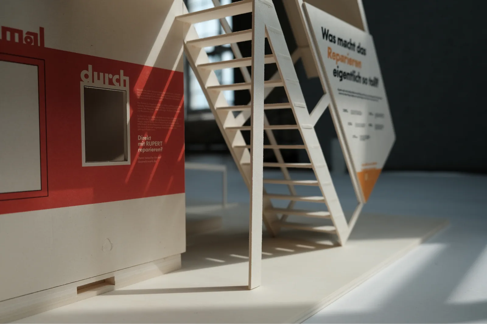 Modellfoto: die rote Fläche „Guck mal durch“ mit Bildschirm, rechts die Treppe zur Plattform.